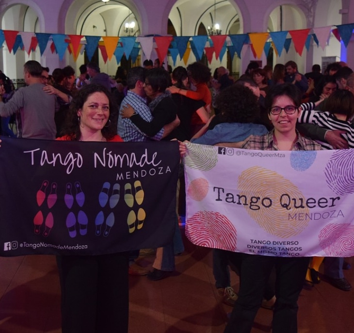 Cingolani y Alfonso sosteniendo carteles de Tango nómade y Tango queer
